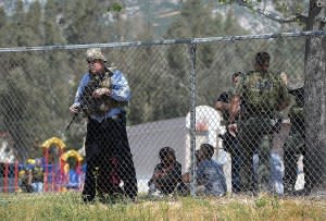 Police stand watch over students as multiple law enforcement agencies respond to a fatal shooting at North Park Elementary School in San Bernardino, California, on Monday.