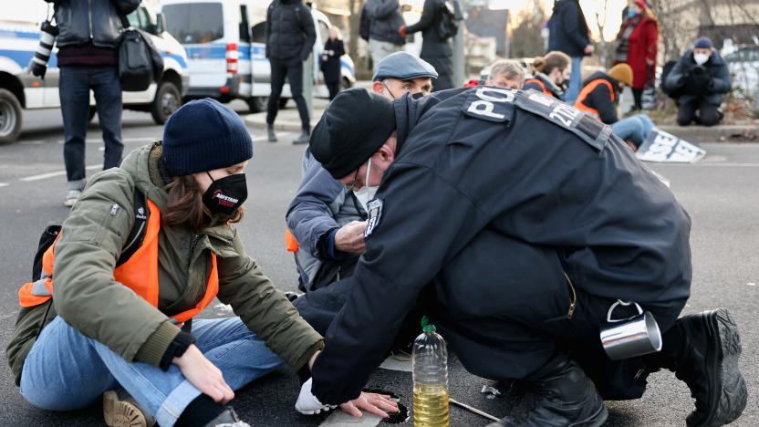 A police officer unglues a "Letzte Generation" (Last Generation) activist's hand from the road during a protest against food waste and in support of an agricultural change to reduce greenhouse gas emissions, in Berlin, Germany, February 14, 2022. REUTERS/Christian Mang