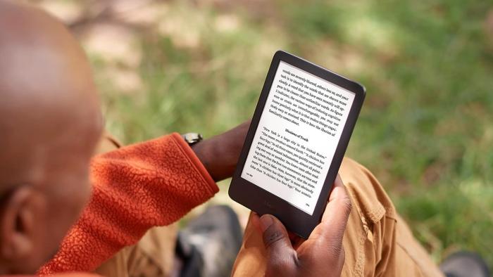 A bald man reading a Kindle.