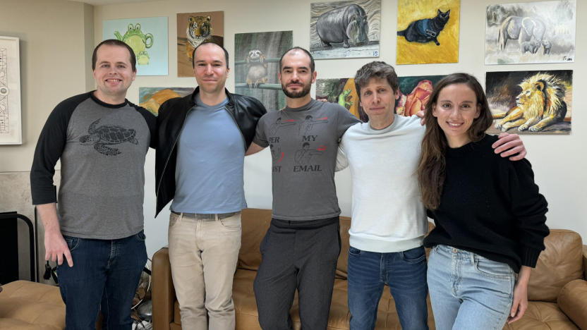 Five people standing next to each other with couches and artwork in the background.