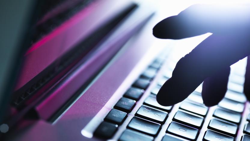 Close up of silhouetted male hand typing on laptop keyboard