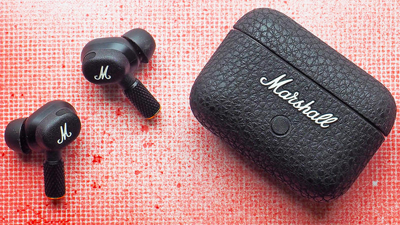 The Marshall Motif II ANC earbuds and charging case with a gridded red spray paint background.