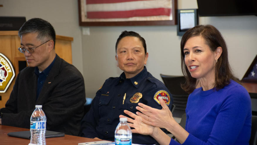 A man in black, a cop and a woman wearing a blue top sitting together.