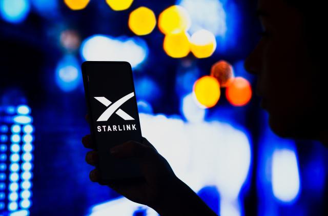 BRAZIL - 2022/05/02: In this photo illustration, a silhouetted woman holds a smartphone with the Starlink logo displayed on the screen. (Photo Illustration by Rafael Henrique/SOPA Images/LightRocket via Getty Images)