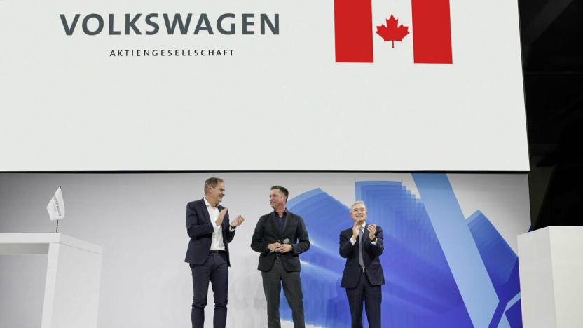 Volkswagen Group CEO Oliver Blume; Thomas Schmall, Group Board Member Technology; and Hon. François-Philippe Champagne, Canada’s Minister of Innovation, Science and Industry stand on stage in front of a screen displaying a Volkswagen logo and the Canadian flag.