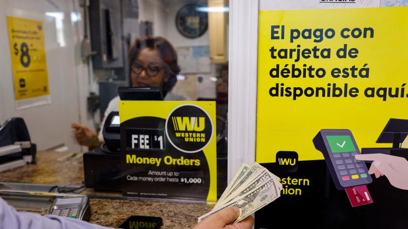 A person holds cash in his hand next to Western Union signs at a Florida Check Cashing window inside a convenience store in Miami, Florida, on January 12, 2023. - Western Union announced January 11, 2023 it had resumed moving money from the United States to Cuba, more than two years after sanctions forced the US-based firm to shut down operations on the communist-run island. The resumption of money transfer services to Cuba "is currently in a test phase," the company said in a statement, noting that US customers are limited to sending a maximum of $2,000 per day and only from select sites in the Miami area. (Photo by Eva Marie UZCATEGUI / AFP) (Photo by EVA MARIE UZCATEGUI/AFP via Getty Images)