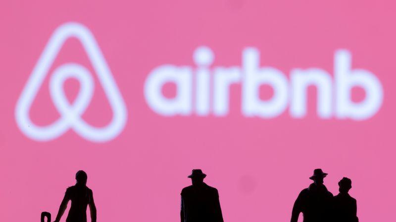 Figurines are seen in front of displayed Airbnb logo