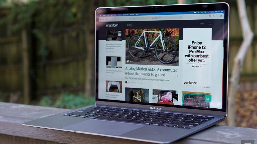 A MacBook Air laptop perched on top of a wooden baluster with trees in the background.                                