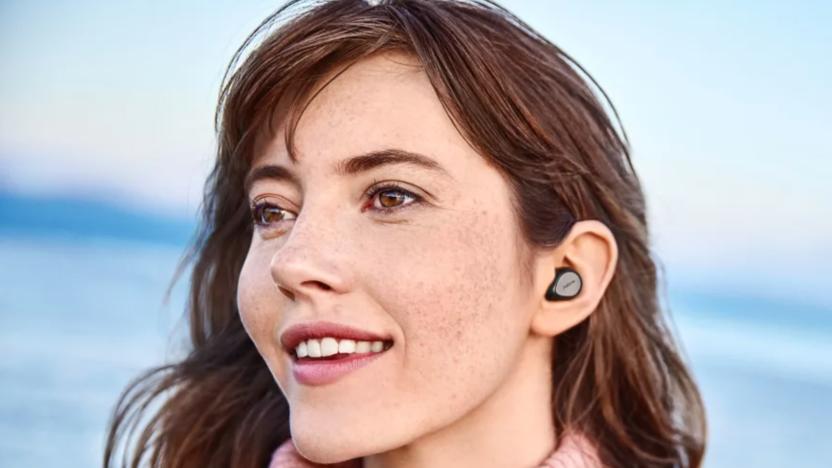 A lady wearing earbuds on the beach living life to the fullest.