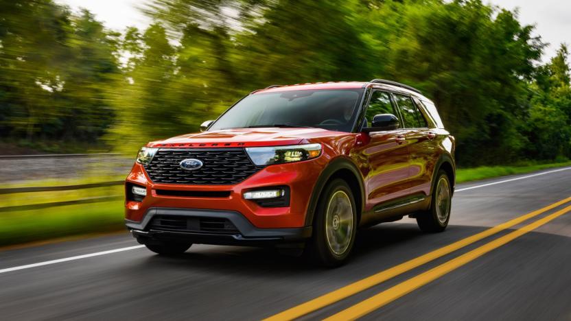 A red Ford Explorer drives down a parkway with trees alongside the road.