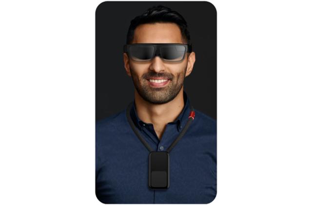 A mockup of Motorola and Verizon's "5G neckband" on a man. He is wearing black VR glasses on his face and a credit card-sized pendant around his collar.