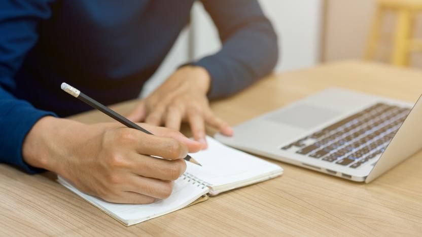 close up man hand holding pencil and copy writing form laptop to note book for summary about learning online course , technology education concept