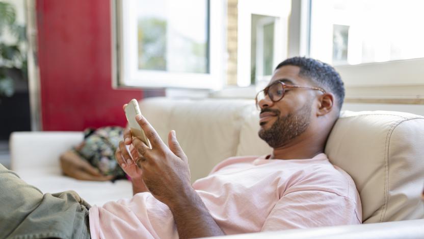 Relaxed man sitting on sofa using cell phone