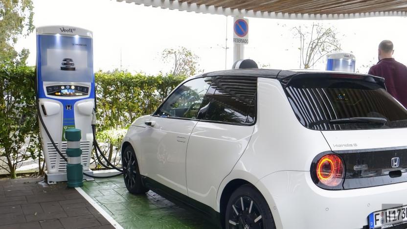 A small white Honda car sits at an EV station.