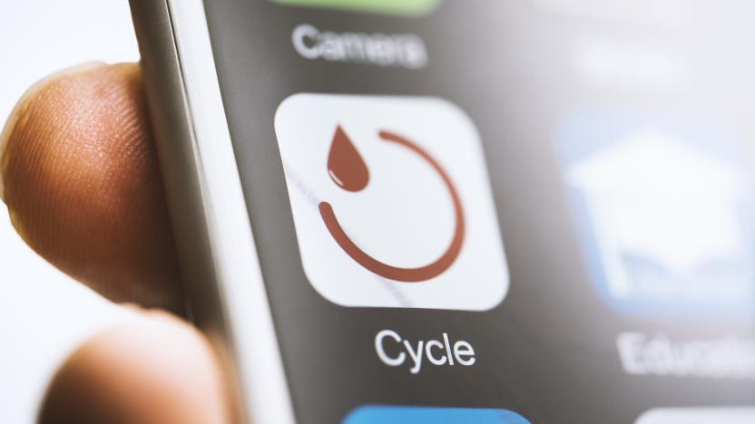 Hand holding smart phone app menstruation cycle icon on touchscreen. Close-up selective focus shot.