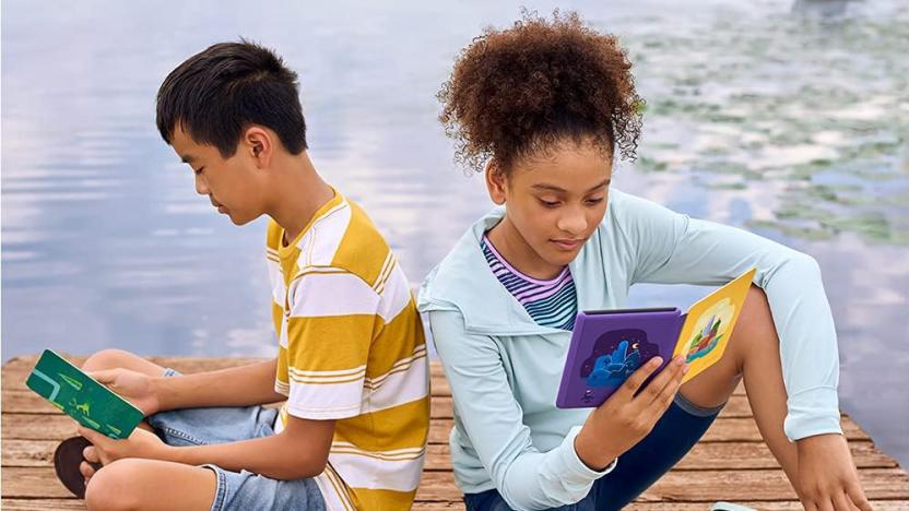 Two kids sitting on a dock with Kindle Paperwhite e-readers encased in colorful cases open in their hands. 