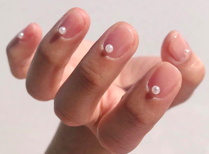 Our favorite nail art trend of the season is single pearls glued onto nails and finge...