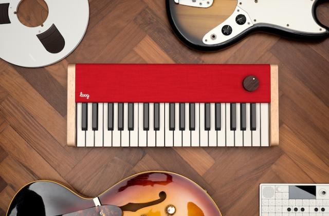 An image of Loog's Piano surrounded by guitars and tape reels. 