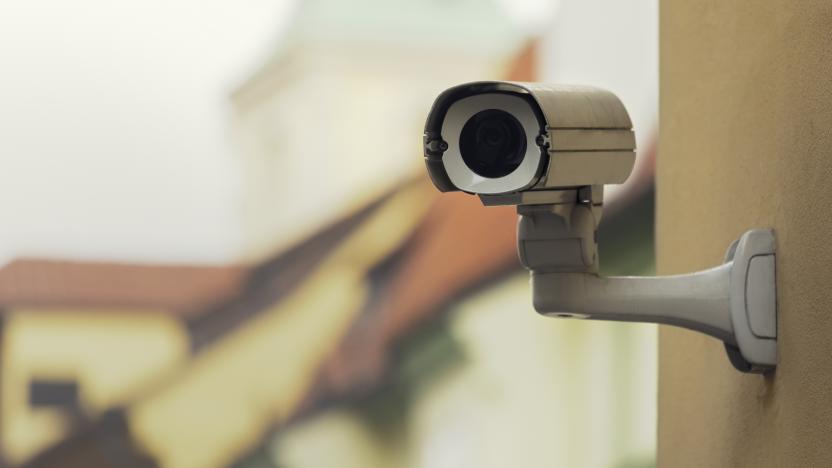 A security camera on an apartment building wall in a city environment.