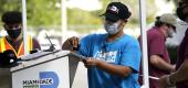 An election worker stamps a vote-by-mail ballot dropped off by a voter before placing it in an official ballot drop box in Doral, Fla. (AP Photo/Lynne Sladky)