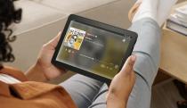 A person sitting comfortably, legs kicked up, reading the Fire HD 8 tablet.