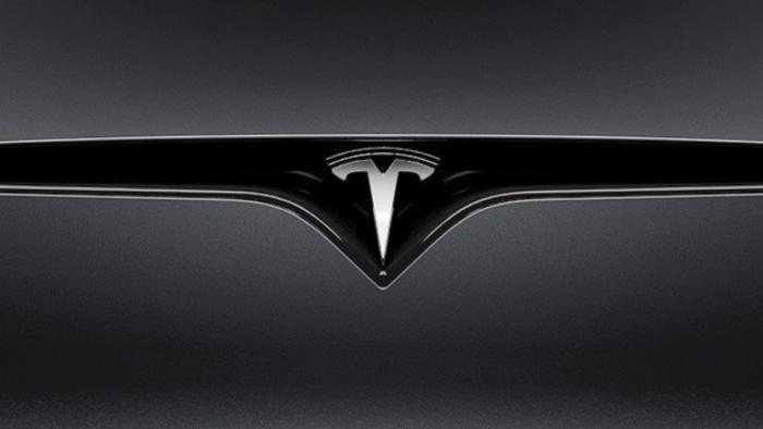 Closeup of a Tesla logo on a car.