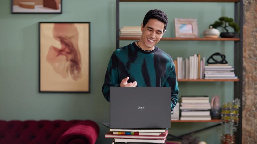 A man in a modern living room smiling as he uses his LG Gram laptop
