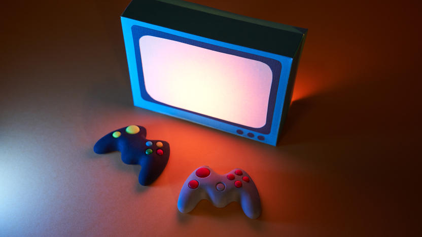 High angle view of two game controllers in front of a retro-style television. The screen light illuminates the game controllers. Video games concept.