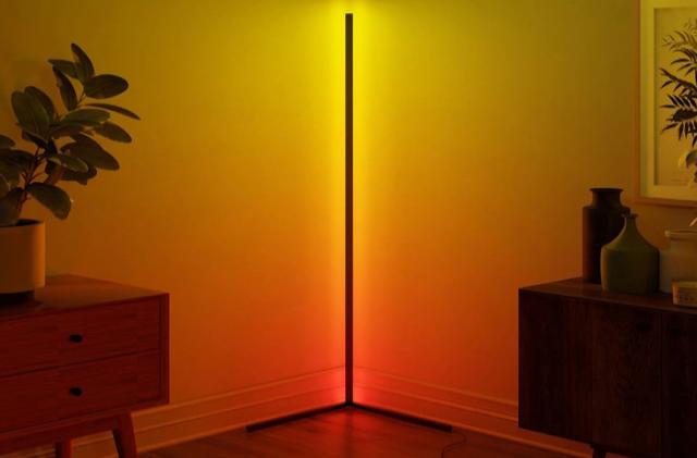 The Minimalist LED Corner Floor Lamp glows orange and sits between two wooden console tables.
