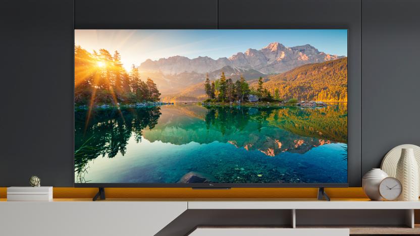 TCL's Google TV-powered 55" 6-series set, showing an image of a lake and mountains, and sitting on a display unit.