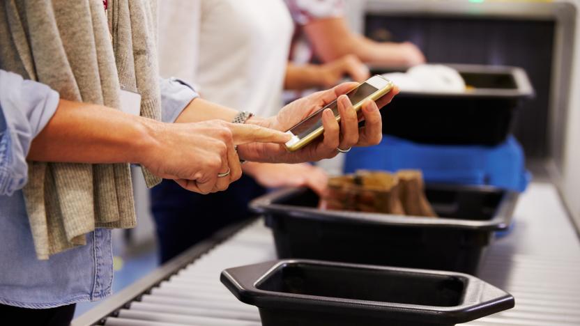 Man Checking Mobile Is Charged At Airport Security Check