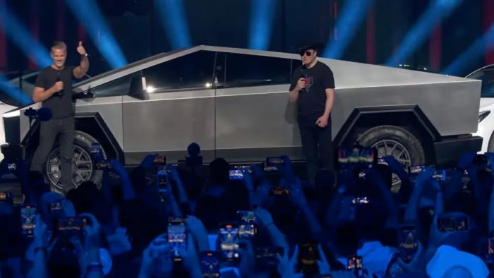 Elon Musk standing next to a Cybertruck.