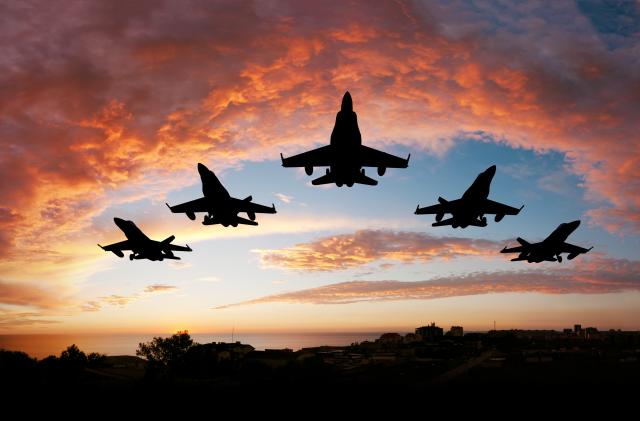 Five fighters flying at sunset