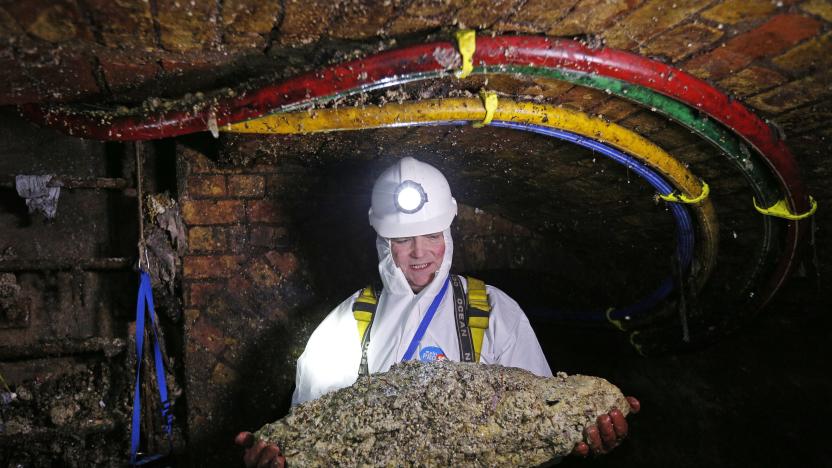 TO GO WITH AFP STORY BY ROBIN MILLARD
Tim Henderson, a "flusher" or trunk sewer technician holds a "fatberg" as he works in the intersection of the Regent Street and Victoria sewer in London on December 11, 2014. Every day beneath the streets of London, sewer cleaners are fighting a grim war against giant "fatbergs" clogging the system. Congealed fat is blocking up the Victorian sewers and the problem is to get worse at Christmas. An extra two Olympic-sized swimming pools of turkey fat will be tipped down the drains during the festive season. There are 80,000 fatberg blockages a year, costing Thames Water customers £1 million ($1.6 million, 1.3 million euros) each month to tackle. The company urges people people to dispose of their cooking oil and fat properly. "Bin it, don't block it" is their message. AFP PHOTO / ADRIAN DENNIS        (Photo credit should read ADRIAN DENNIS/AFP via Getty Images)