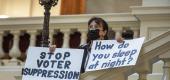 Ann White of Roswell, Ga., holds protest signs at the Georgia state Capitol in Atlanta on March 25. (Alyssa Pointer/Atlanta Journal-Constitution via AP)