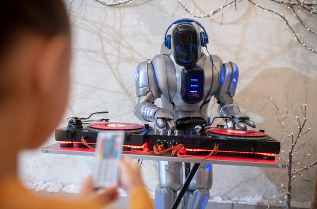 Robot dj. Girl making a selfie of her digital friend standing near dj table