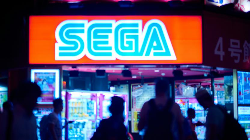 A group of people walk past a Sega sign.