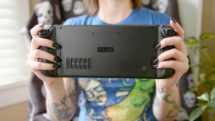 A woman holds up a Steam Deck handheld console with the back of it facing the camera.