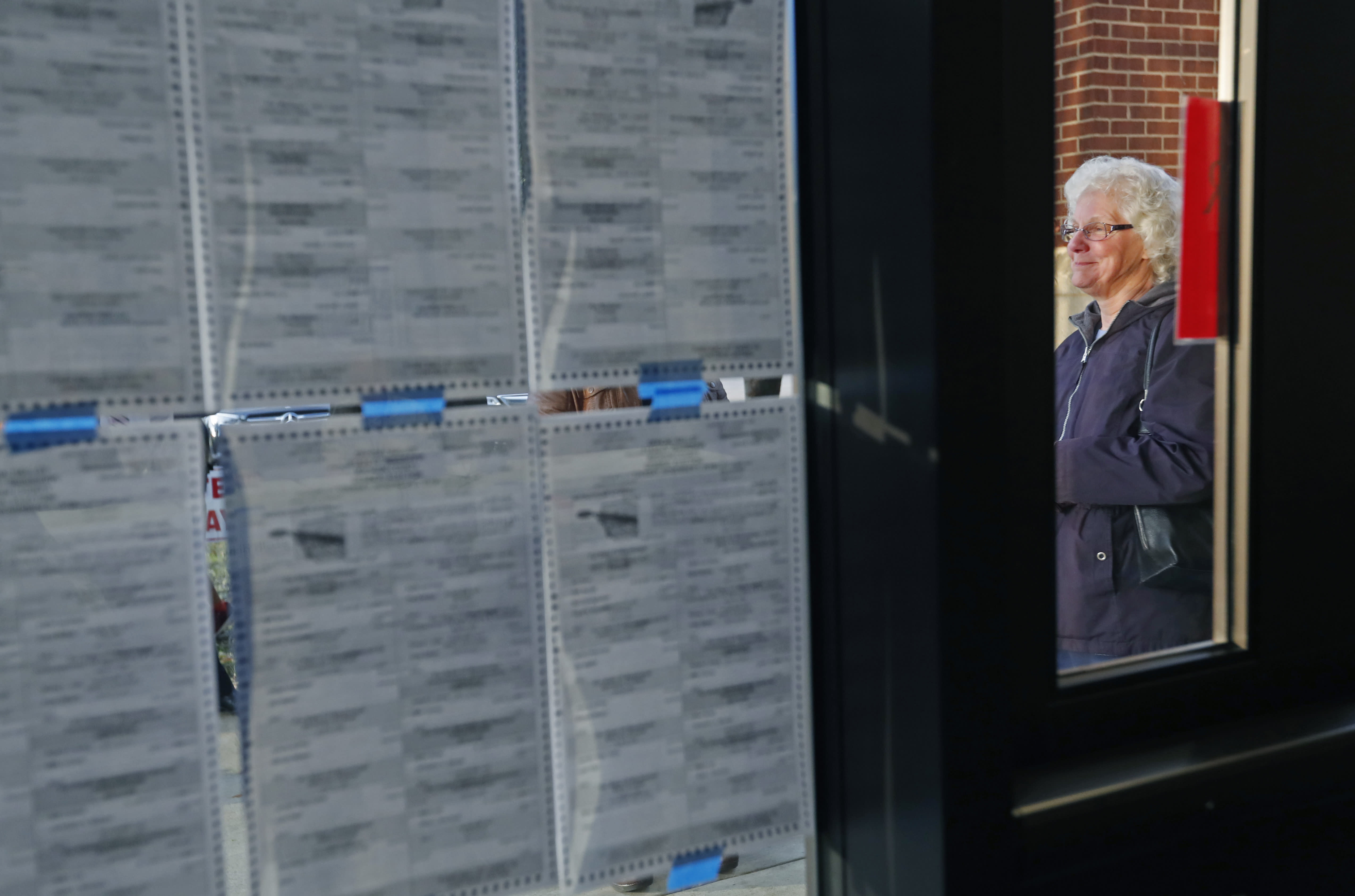 Fran McNeill, and others can study the candidates and races as they wait for the Ridgeland, Miss., precinct to open its doors, Tuesday, Nov. 5, 2019. Registered voters are having their say in Mississippi's most hotly contested governor's race since 2003 and are also selecting six other statewide officials and deciding a host of legislative and local offices. (AP Photo/Rogelio V. Solis)