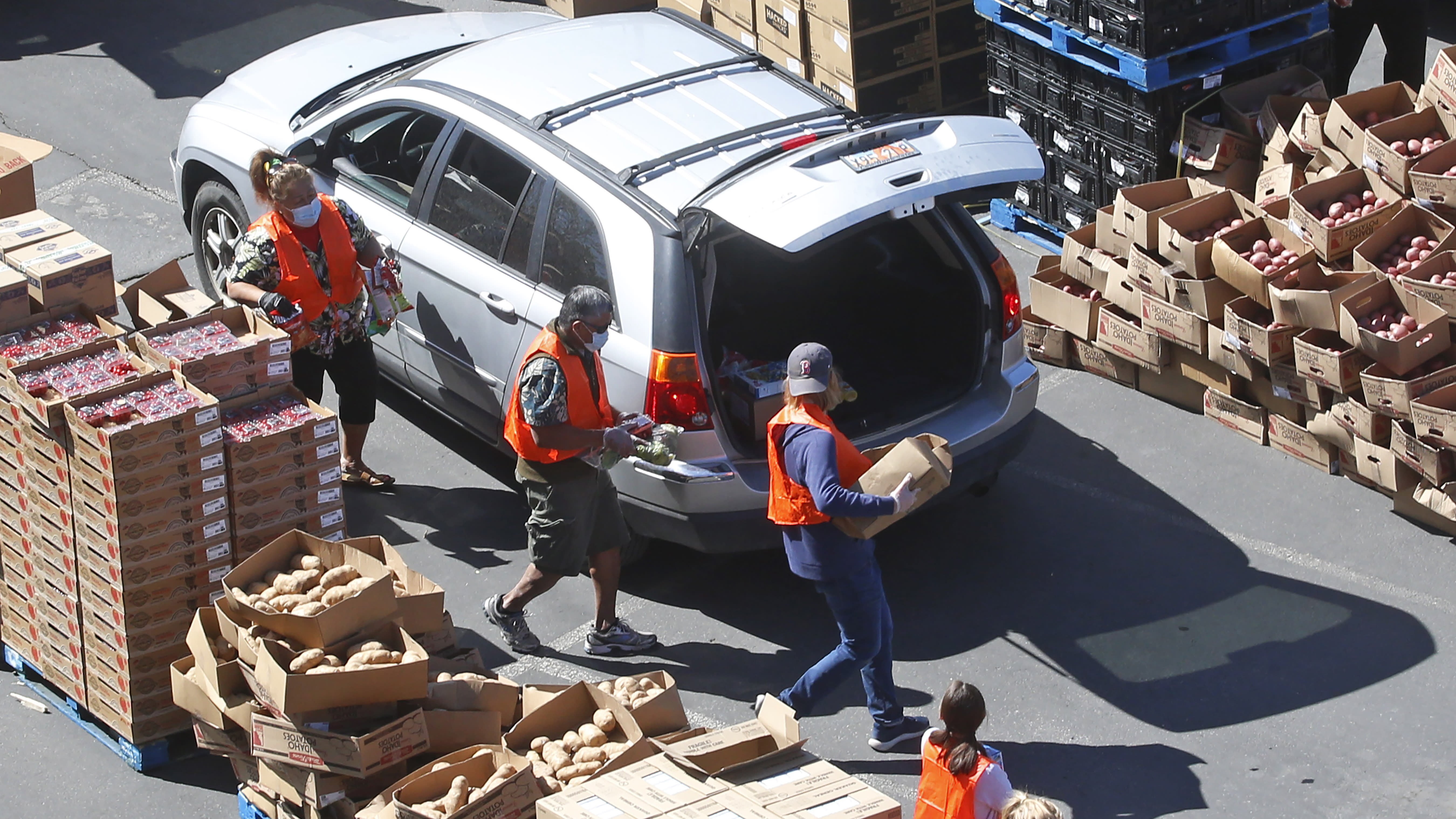 Volunteers load food in a vehicle at the Utah Food Bank's mobile food pantry at the Maverik Center Friday, April 24, 2020, in West Valley City, Utah. As coronavirus concerns continue, the need for assistance has increased, particularly at the Utah Food Bank. (AP Photo/Rick Bowmer)