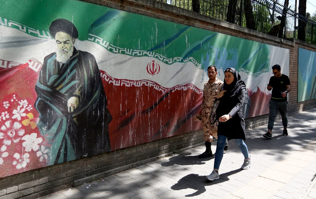 People walk past a mural depicting the founder of the Islamic republic Ayatollah Ruhollah Khomeini and painted on the walls surrounding the former US embassy in the Iranian capital on June 22, 2019 amid an escalation between Washington and Tehran (AFP Photo/ATTA KENARE)