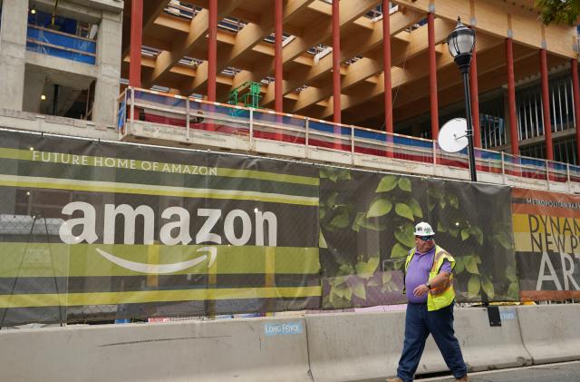 A construction worker passes a job site at Metropolitan Park, the first phase of new construction of Amazon's HQ2 development Arlington, Virginia October 13, 2021. REUTERS/Kevin Lamarque