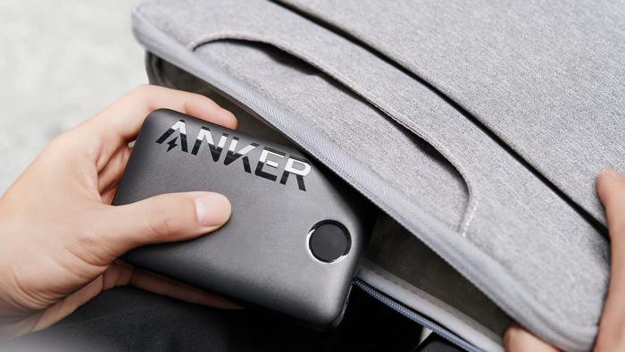 A black Anker-branded portable battery being inserted into a  bag.