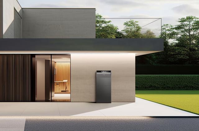 Anker's new Solix home energy storage with modular solar battery system is displayed outside of a modern home, appearing as a slim grey appliance against an outer wall (protected by an overhanging roof).