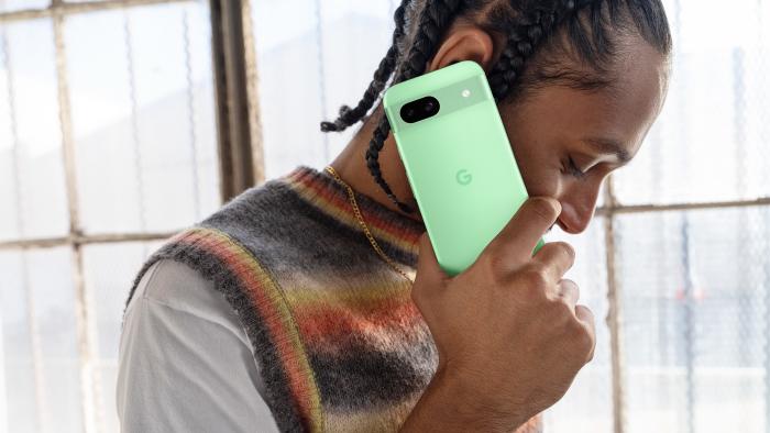 A person holds the new Pixel 8a in the Aloe colorway.