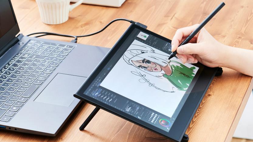 An artist draws on a Wacom Movink pen display that's connected to a black laptop.