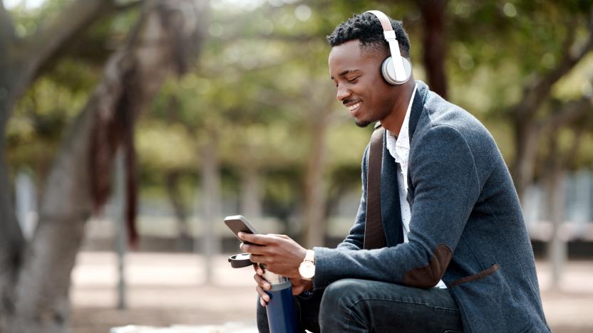 Shot of a young businessman using a smartphone and headphones in the city