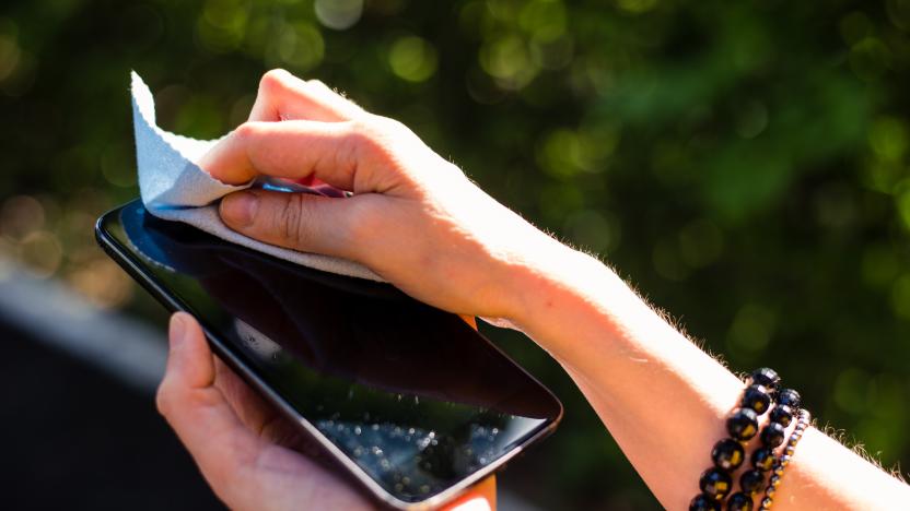 Young person’s hands holding black smartphone while cleaning it with blue cloth – Young female washing mobile phone screen with soft fabric from dust