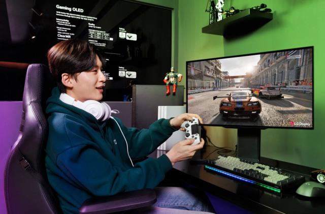 A young man plays a racing game on a fancy display. 