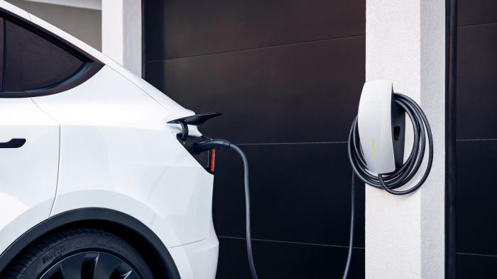 A white car attached to an electric charger installed on a beam.